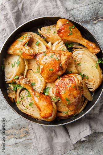Baked chicken pieces with cabbage in soy sauce and honey close-up in a frying pan on the table. Vertical top view from above