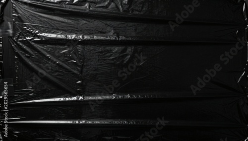 Dramatic black plastic sheet with crinkles and light reflections for abstract background texture