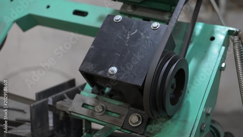 An electric motor with pulleys and a drive belt in the production room of the workshop