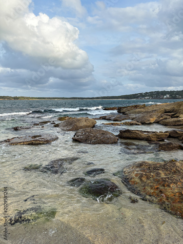 View of rocky beach shore with blue sky.