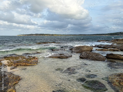 View of rocky beach shore with blue sky.