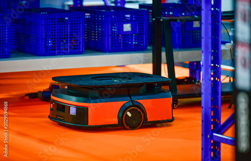 Photos Autonomous mobile robot AMR navigating through modern smart warehouse floor