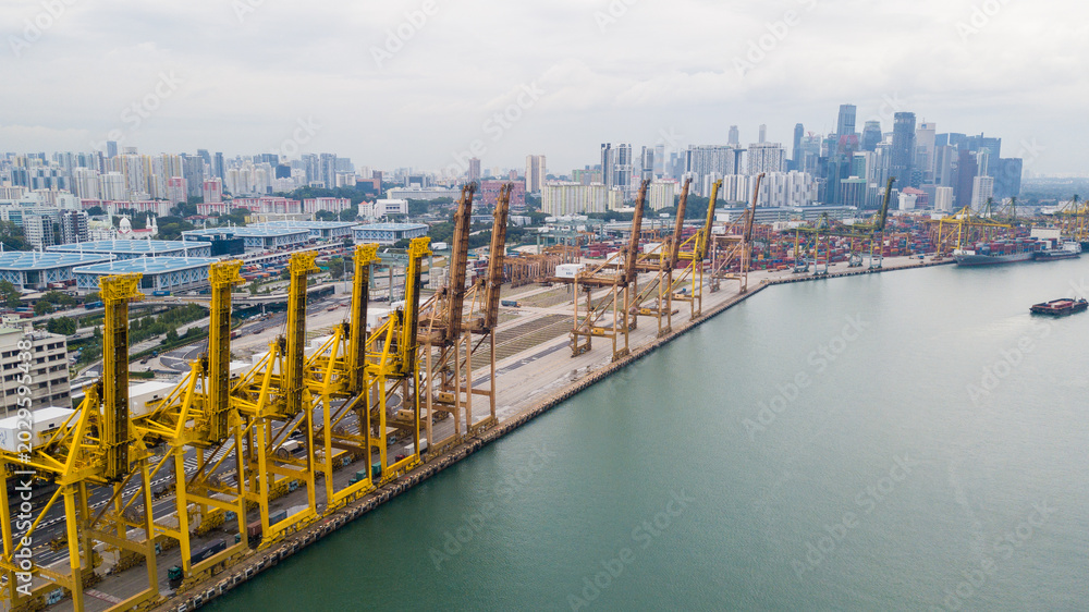 Obraz premium Aerial View of Industrial Shipping Port with Yellow Cranes and City Skyline