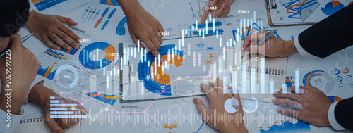 Obraz na plátne Business professionals collaborate in a meeting, analyzing financial data and graphs on a table, enhanced by digital graphic overlays for visual impact