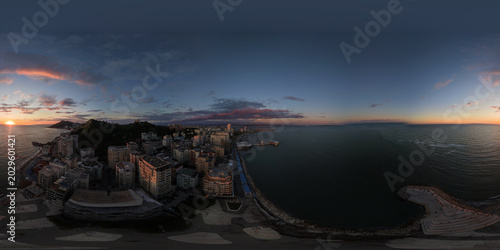 Photos Blue-hour aerial panorama of a curving bay, waterfront high-rises and deepening evening sky over the sea