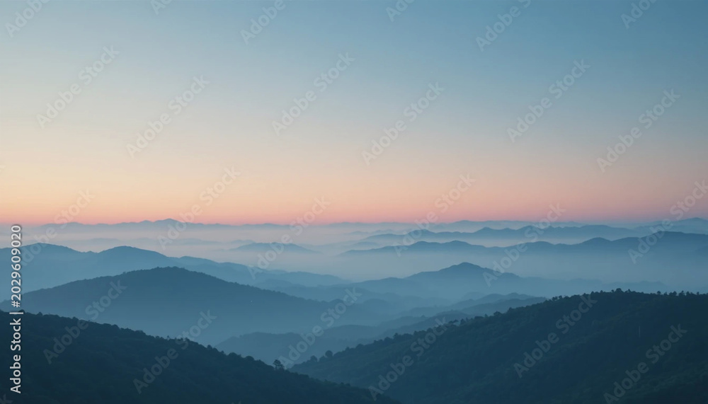 Obraz premium Serene mountain landscape at sunrise with misty valleys and rolling hills under a gradient sky