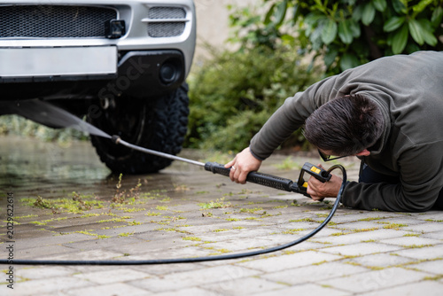 Man cleaning off-road vehicle with pressure washer