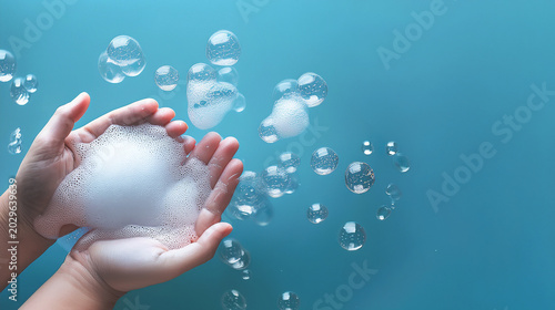 Close up of soap foam washing on child's hands and floating bubbles on pastel  background.