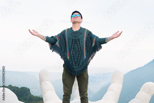 Man enjoying freedom standing on giant hand sculpture