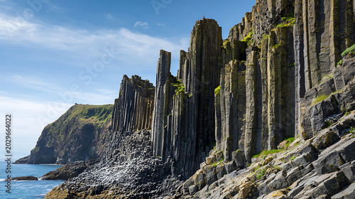 Vertical Basalt Rock Pillars on a Steep Coastal Cliff Under a Bright Blue Summer Sky