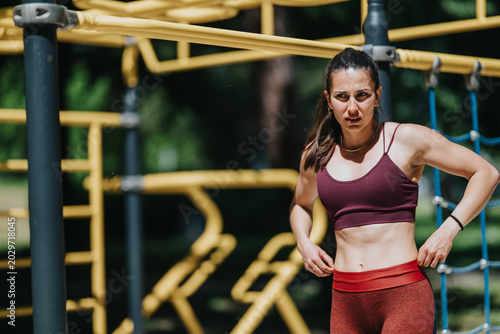 Canvas Print Young woman in sportswear adjusts her waistband while taking a break from exercise