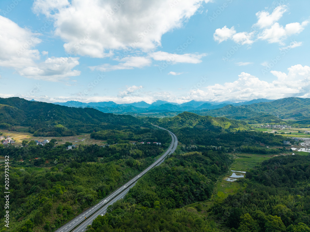 Obraz premium A high angle aerial view of a highway stretching through the green mountains and landscape of Wuyi Mountain in Fujian China