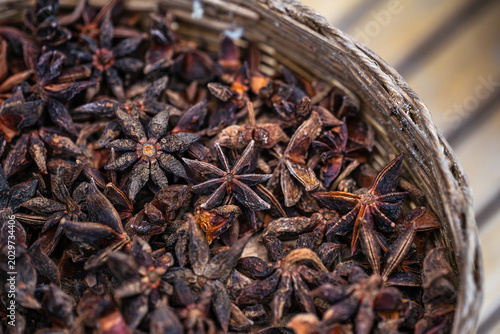 Foto Dried star anise pods, known for their unique star shape and potent aroma, are presented in a rustic woven basket