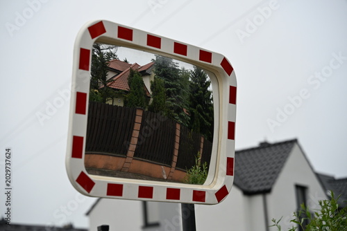 Road Mirror Reflecting Wooden Fence in Rural Surroundings