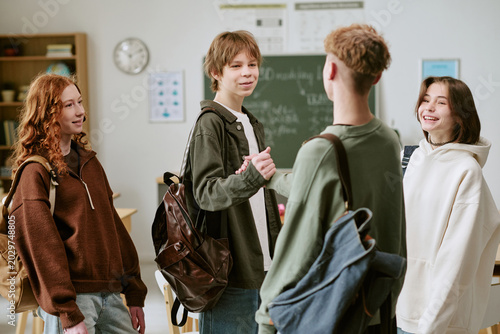 Fotografi Teenagers greeting and chatting in classroom, building peer connection and schoo