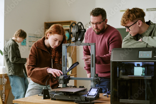 Canvas Print Teenagers and middle aged male teacher operating 3D printers during classroom wo