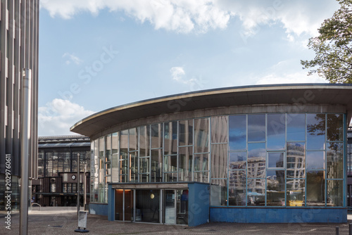 Foto An eye-level architectural photograph of the Tränenpalast, a historical border crossing building located near Friedrichstraße station in Berlin, Germany, featuring a modern glass facade, blue tiled