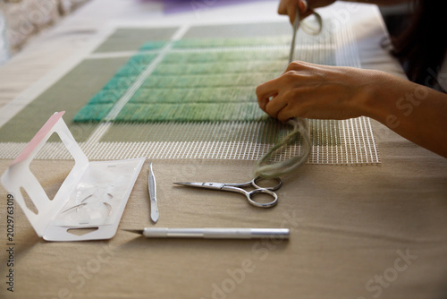 Artist creating textile artwork using needles and yarn, designing abstract patterns