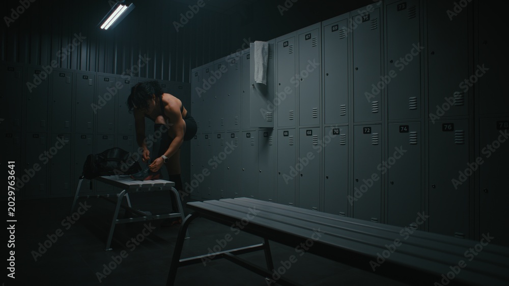 Naklejka premium Young Sporty Woman Changes Clothes Before Training Session in Locker Room, Putting on Athletic Sneakers, and Tying Shoelaces. Fitness Lifestyle, Discipline, Motivation, and Active Healthy Routine.