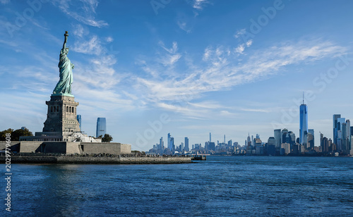 Statue of Liberty with New York City skyline under clear blue sky, iconic landmark and urban panorama.