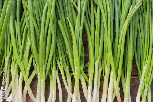 Schilderij op canvas Organic green onion stalks on wooden background with fresh natural vegetable tex
