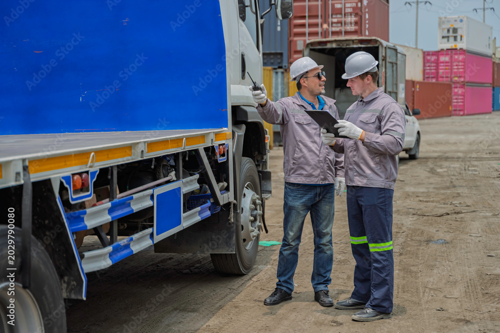 Naklejka premium Professional logistics team performing cargo inspection and safety check on truck trailer in industrial shipping port. Logistics management and commercial transport supply chain services.