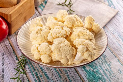 Tableau sur toile Raw cauliflower florets on a ceramic plate on a rustic wooden table