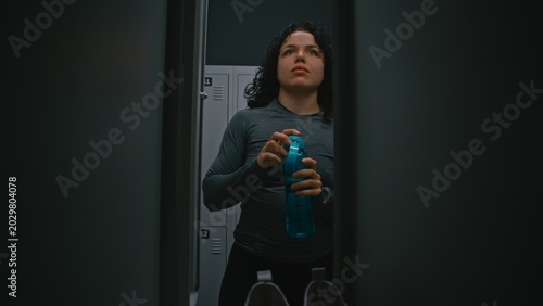 Tableau sur toile Female Athlete Preparing For Workout in Bright Locker Room