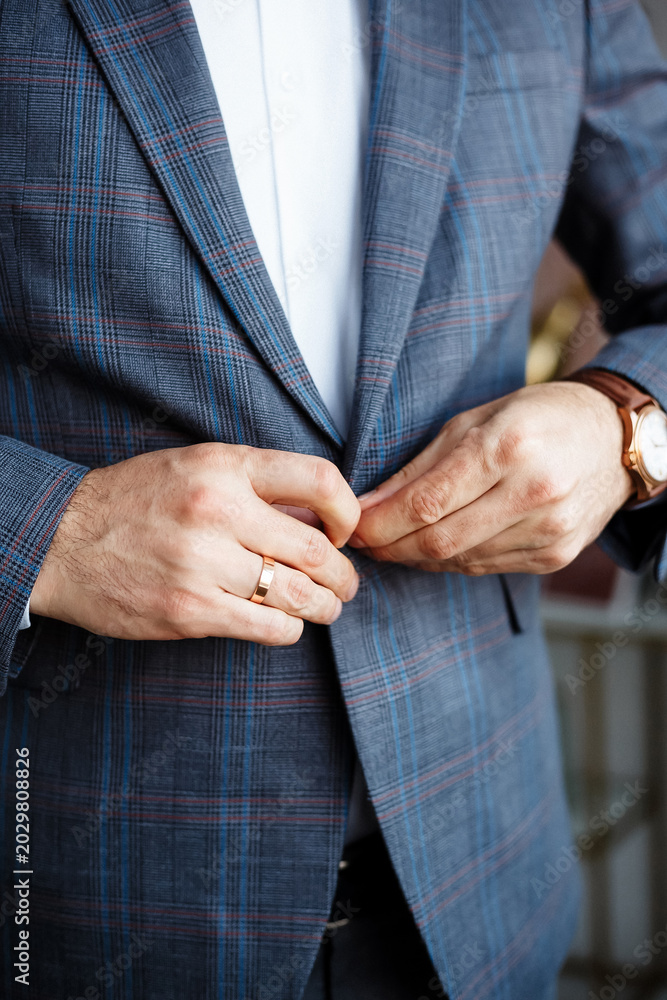Fototapeta premium Businessman in plaid blazer buttoning suit jacket