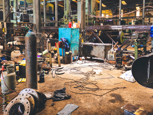 Foto Interior view of a cluttered heavy industrial workshop with gas cylinders, flang