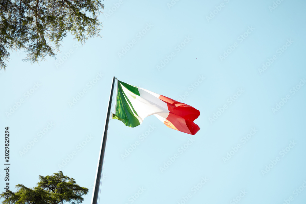 Fototapeta premium National flag of Italy fluttering on flagpole outdoors on a sunny day in Rome.