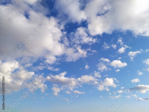 Foto Beautiful blue sky filled with fluffy white cumulus clouds under bright sunlight creating serene and peaceful natural atmosphere during clear daytime