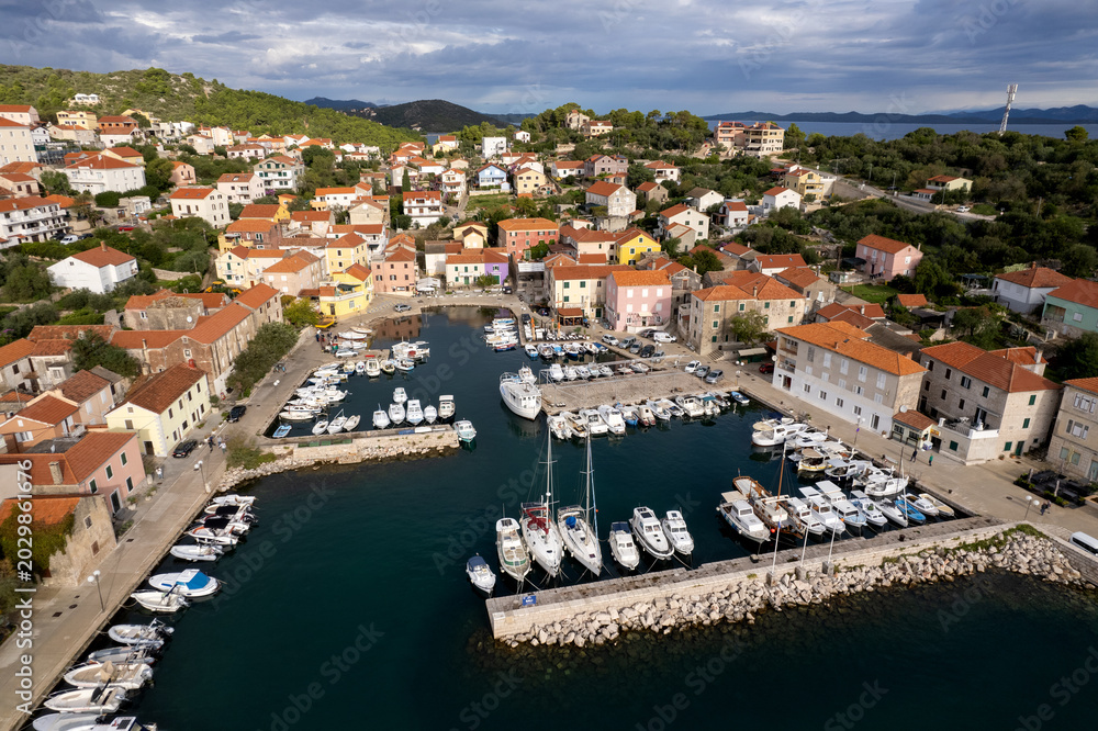 Obraz premium Aerial view of yachts and boats docked in Sali marina, Dugi Otok island, Croatia. Drone shot of beautiful mediterranean port filled with luxury yachts during sunrise.