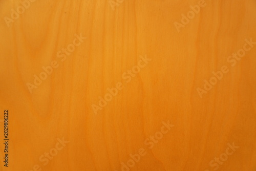 A close-up view of a smooth polished wooden surface with a fine warm-toned vertical grain