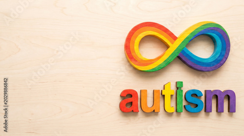 Colorful autism symbol with infinity sign and wooden background  