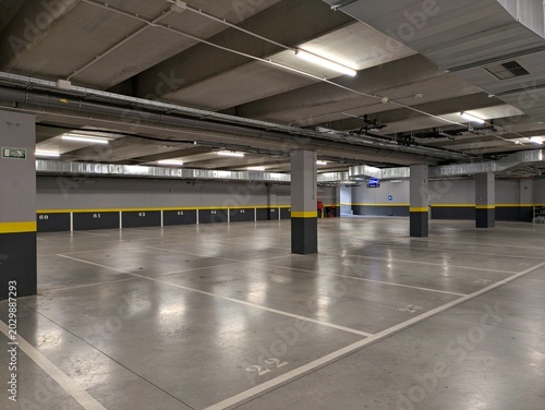 Bild auf Leinwand Garaje subterráneo vacío de supermercado con columnas de hormigón, luces y condu