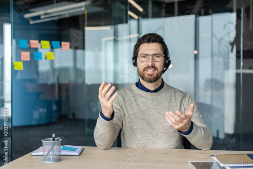 Schilderij op canvas Businessman in glasses and headset providing online consultation, explaining and