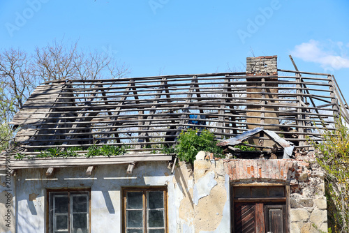 Fotografía Abandoned House with Damaged Roof and Exposed Rafters