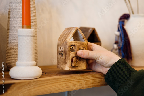 Male hand picking clay candle house in handmade pottery shop.