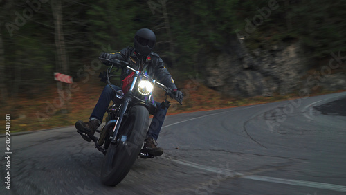 Rider accelerating motorcycle on winding mountain forest road
