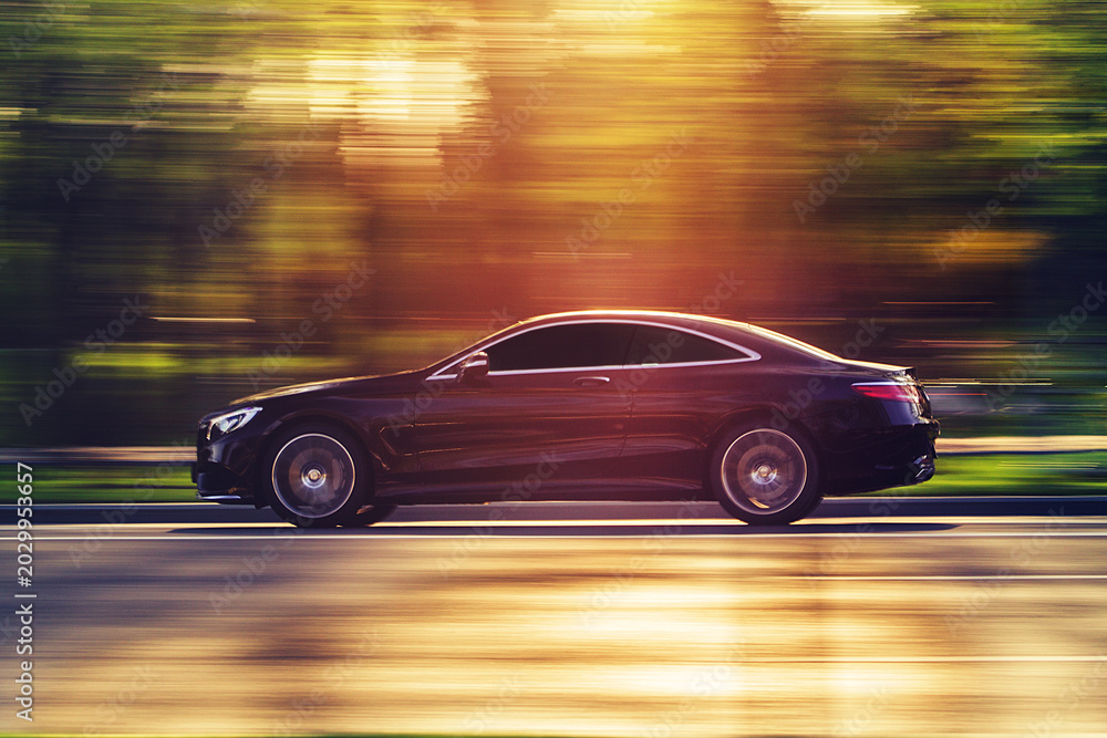 Fototapeta premium Luxury car driving fast with motion blur at sunset
