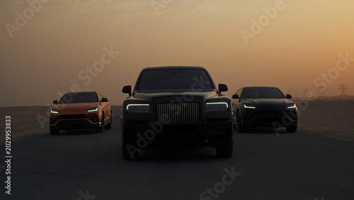 Foto Luxury suvs driving desert road during sunset