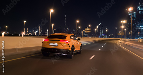 Foto Yellow luxury suv driving on dubai highway at night