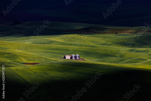 A farm barn within a  lushly green rolling hills