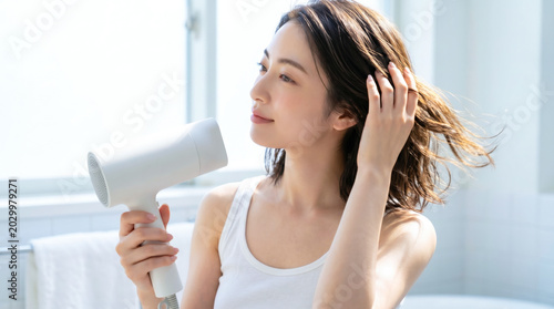ドライヤーで髪を乾かす若い女性 ヘアケア