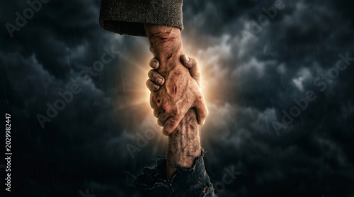 Man hand grabbing another man hand for rescue. Helping hand gesture in storm. Salvation, support, hope and resilience concept. Dramatic background with light shining through the clouds.
