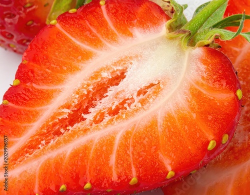 Extreme close-up reveals vibrant red strawberry flesh, seeds, and green stem