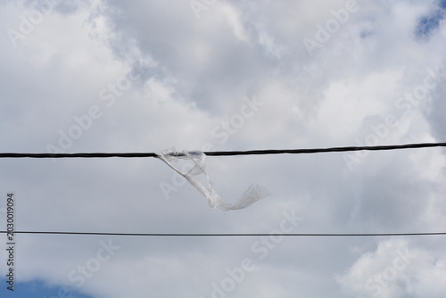 Slika na platnu Wide view of a discarded clear plastic bag tangled and stuck on an overhead powe
