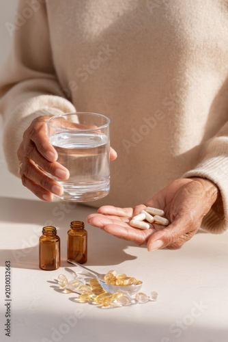 Elderly hands holding supplements and a glass of water for daily health routine and medication management background for healthcare design