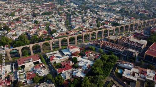 Descending dolly aerial shot above Aqueduct of Queretaro showing traffic intersection and colonial urban landscape in Santiago de Queretaro Mexico during blue hour